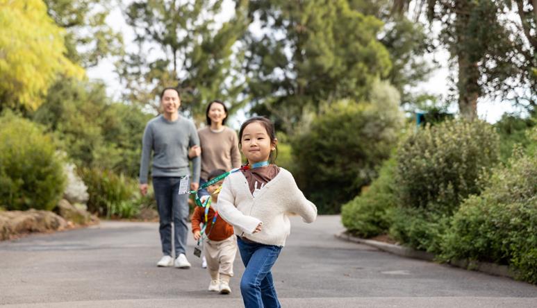 A young guest runs down a path ahead of her family at Melbourne Zoo.